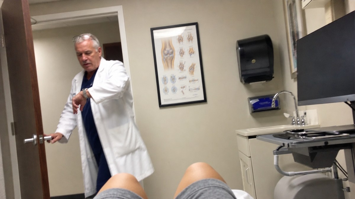 Seen from the exam table — a surgeon in a white coat already heading out the door